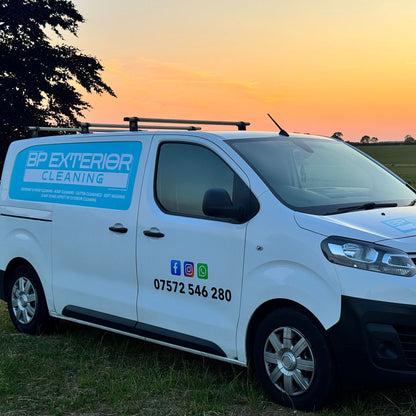 White van with branding on a grassy field at sunset